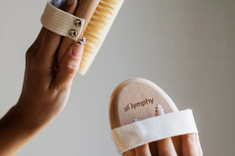 Two hands holding body brushes: one shows the agave bristles, one the wooden back
